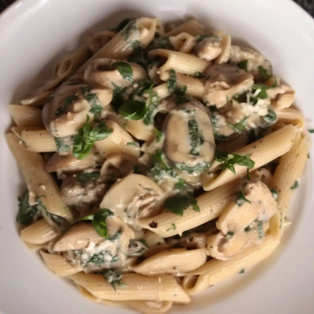 A delicious plate of mushroom spinach pasta with penne in a creamy sauce