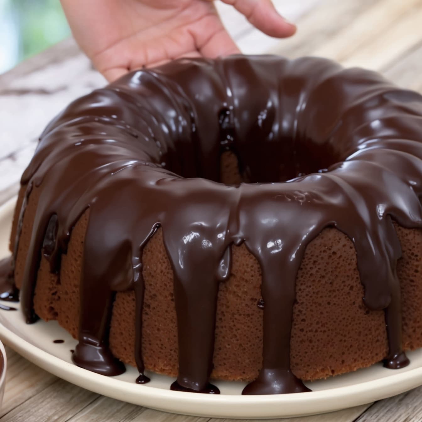 A chocolate cream cheese pound cake baked in a bundt pan and topped with a glossy chocolate ganache.